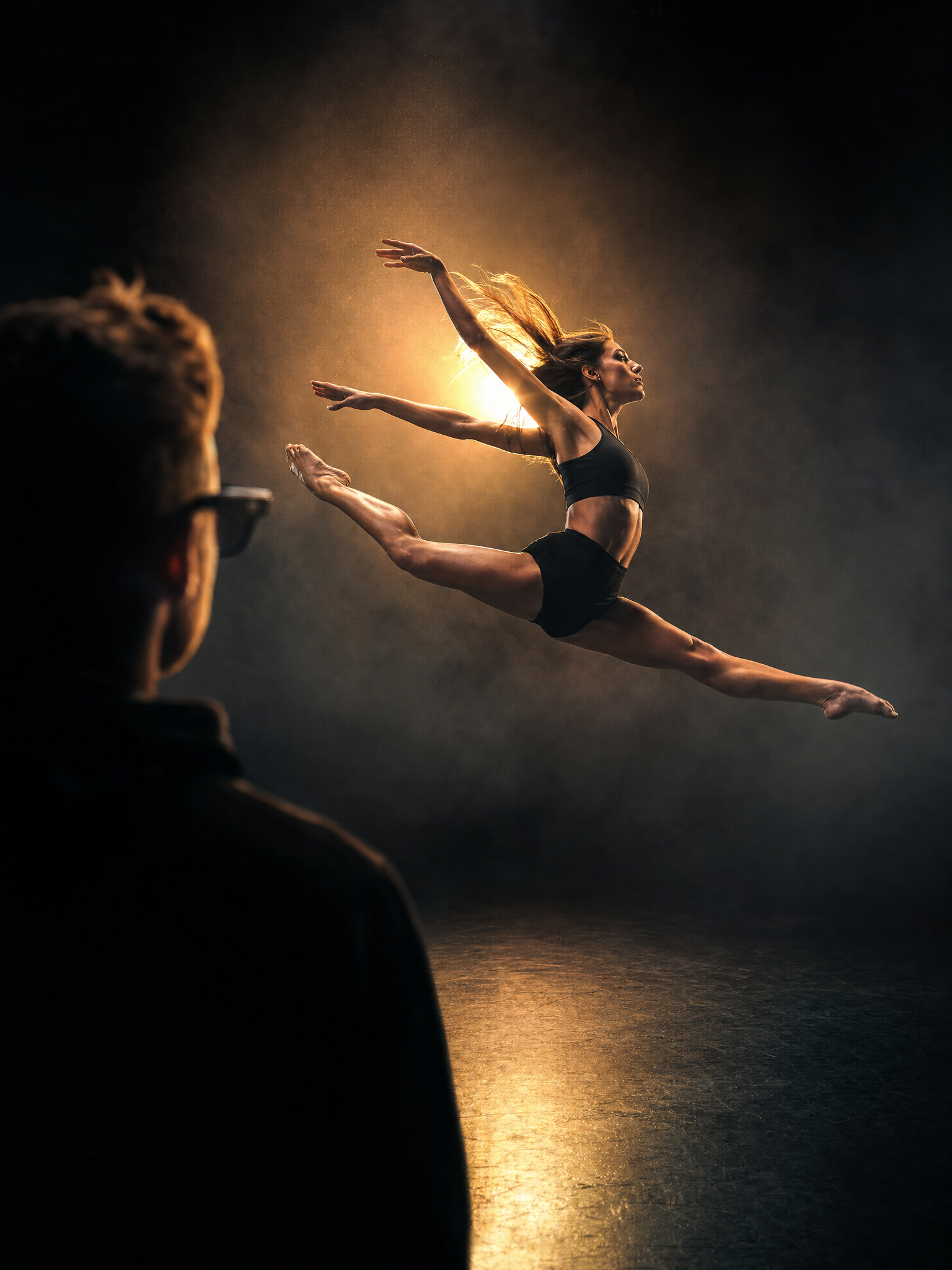 A dancer frozen at the explosive peak of a powerful leap under dramatic rim light